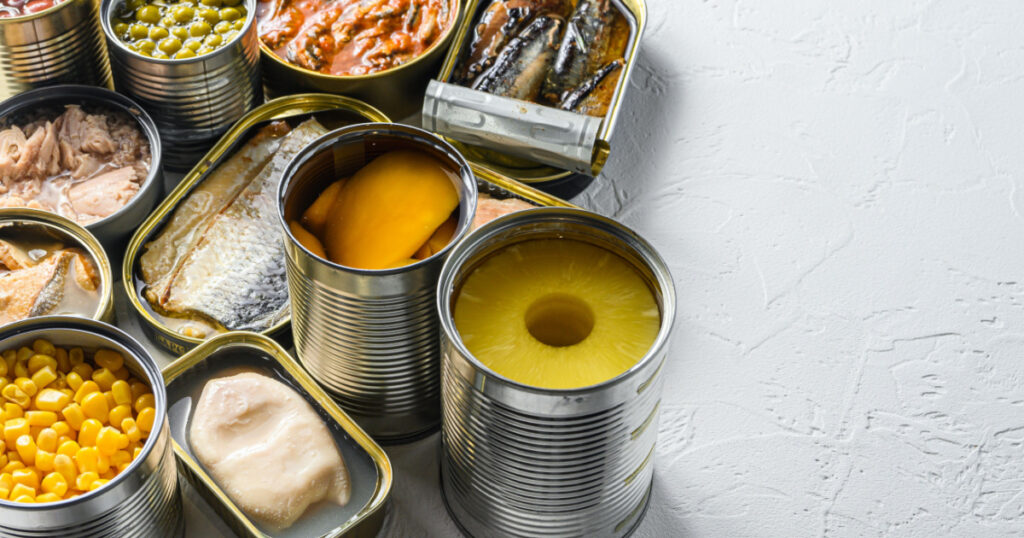 Tin cans for processed food cans conserve Saury, mackerel, sprats, sardines, pilchard, squid, tuna pinapple, corn, peas, mango , beans, over white textured background close up side view space for text