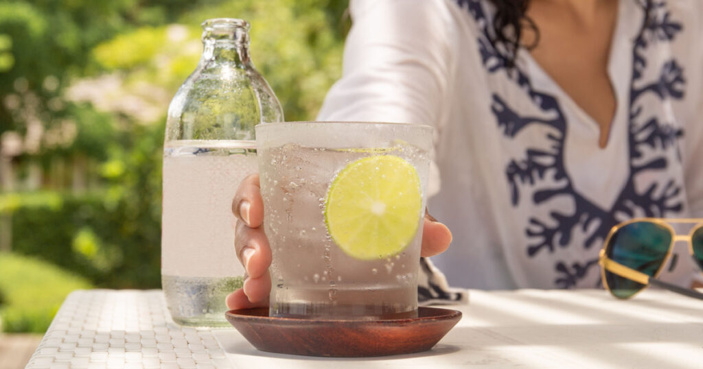 Woman hand reaching glass of healthy nutrition of sparkling water