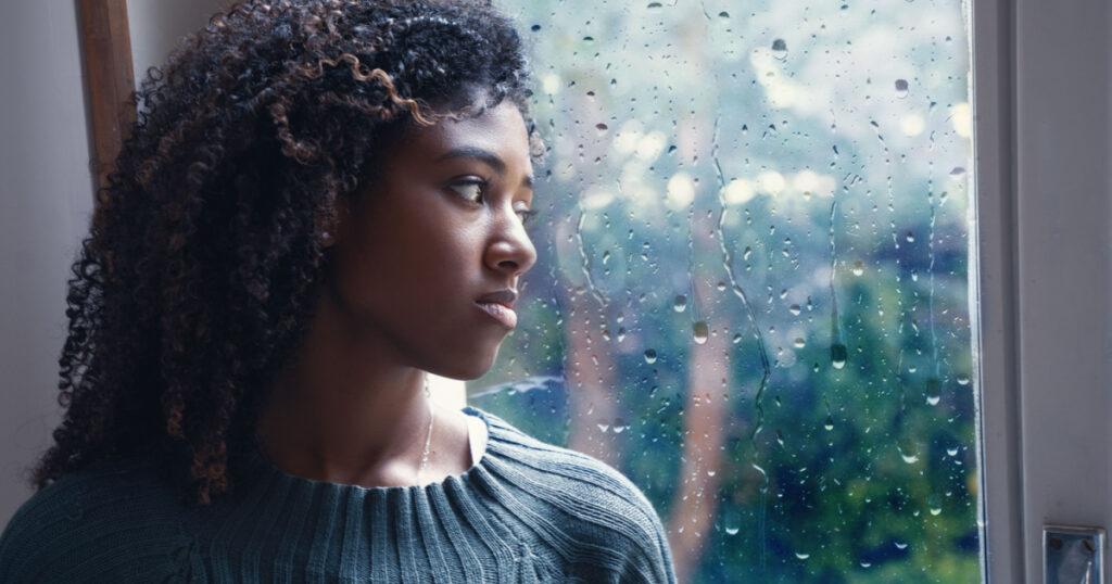 Black woman feeling depression symptoms alone at home
