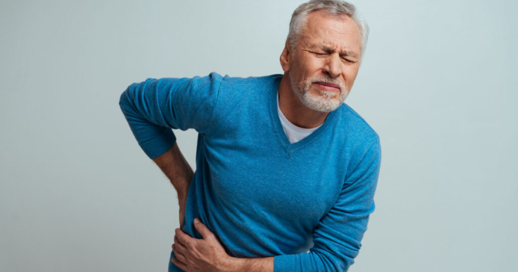 Handsome senior isolated on grey background. Old man feeling pain. Concept about the third age and seniority