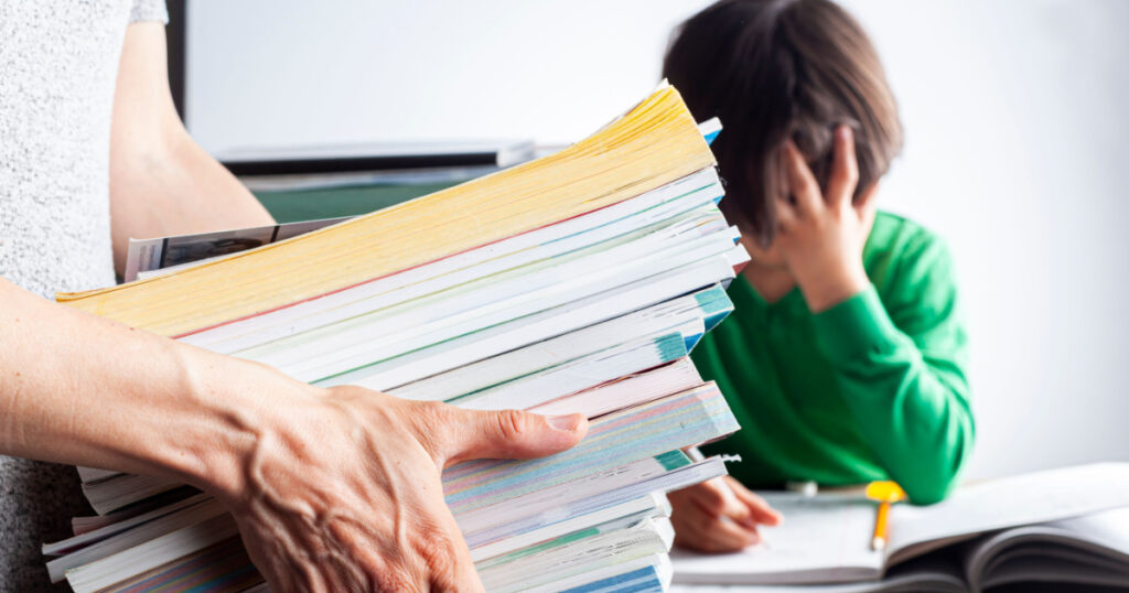 Ambitious parenting with high academic achievement expectations from kids concept. A mother is bringing a pile of test prep books to her bored, tired kid who is crying and protesting during homework