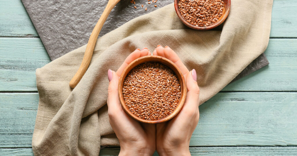 Woman with bowl of flax seeds at table