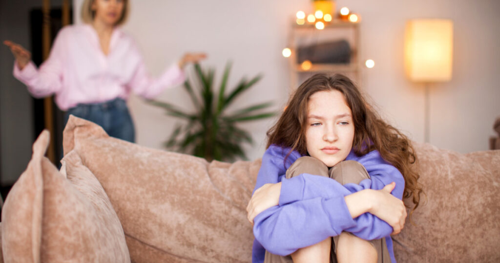 Conflict between mother and child. Woman screams at teenage girl. Sad child feels resentment and hopelessness. Abuse