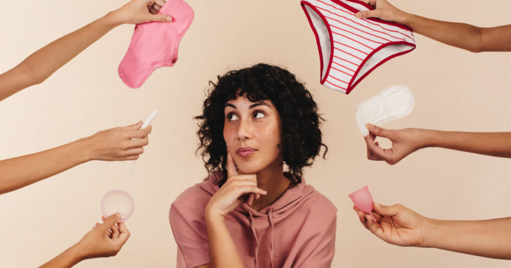 Young woman contemplating the best sanitary choice for her body. Thoughtful young woman looking away while surrounded by hands holding different reusable and non-reusable sanitary products.