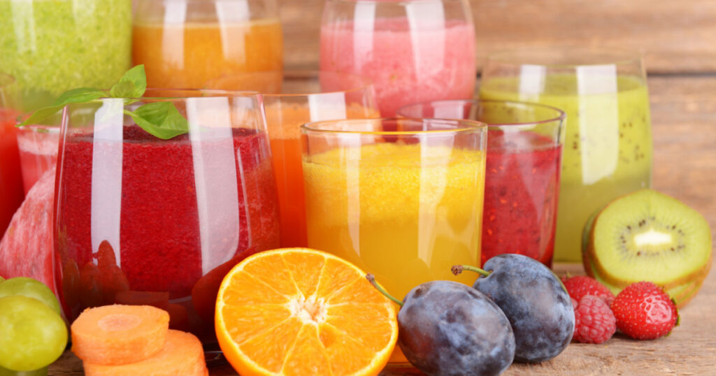 Glasses of tasty fresh juice, on wooden table.