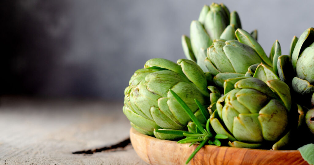 Artichoke flowers in wooden plate. Selective focus.