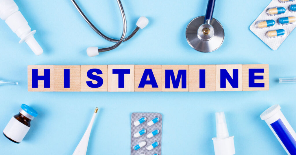 On a blue background, a stethoscope, a thermometer, other medicines and wooden cubes with the text HISTAMINE. View from above. medical concept