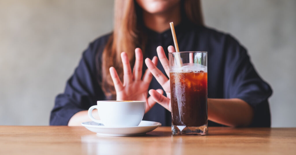 A young woman making hand sign to refuse iced coffee and hot coffee
