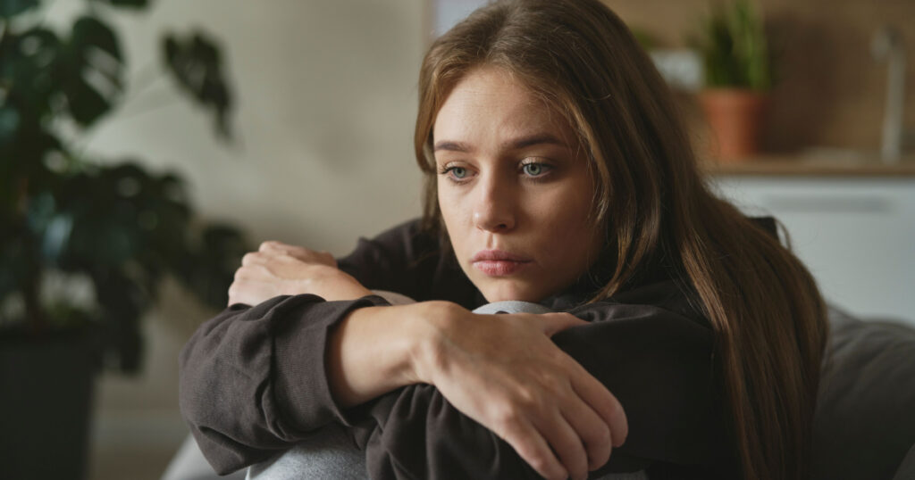 Caucasian sad woman sitting at the sofa with depression
