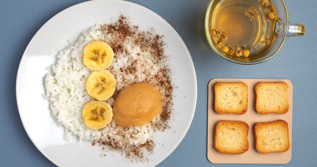 White rice, banana slices, applesauce, toast and chamomile tea. Lunch of BRAT diet meal plan. Flat lay.