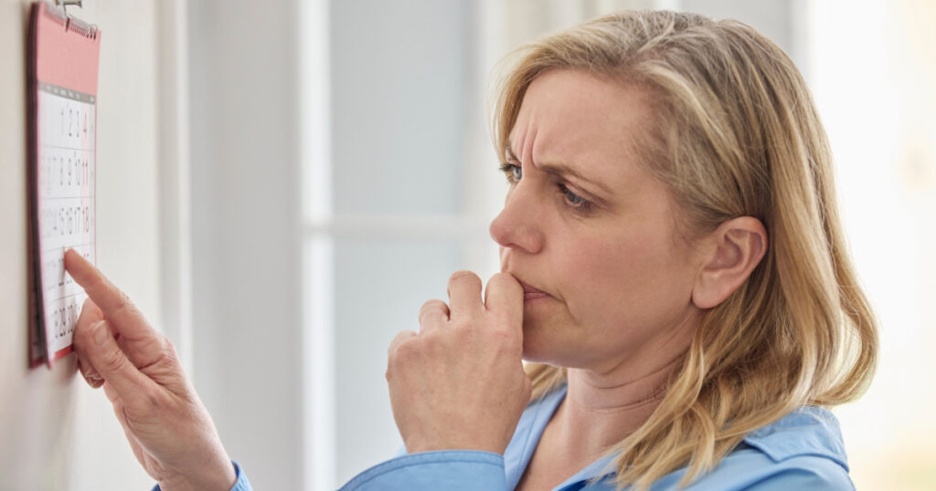 Forgetful Menopausal Mature Woman With Poor Memory Looking At Calendar At Home