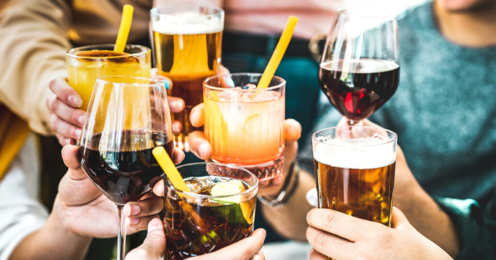 Friends hands toasting fancy cocktails - Young people having fun together drinking beer and wine at happy hour - Social life style party time concept on vivid filter - Focus on lower cuba libre drink