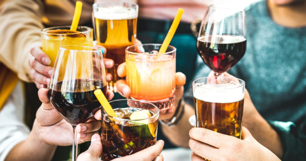Friends hands toasting fancy cocktails - Young people having fun together drinking beer and wine at happy hour - Social life style party time concept on vivid filter - Focus on lower cuba libre drink