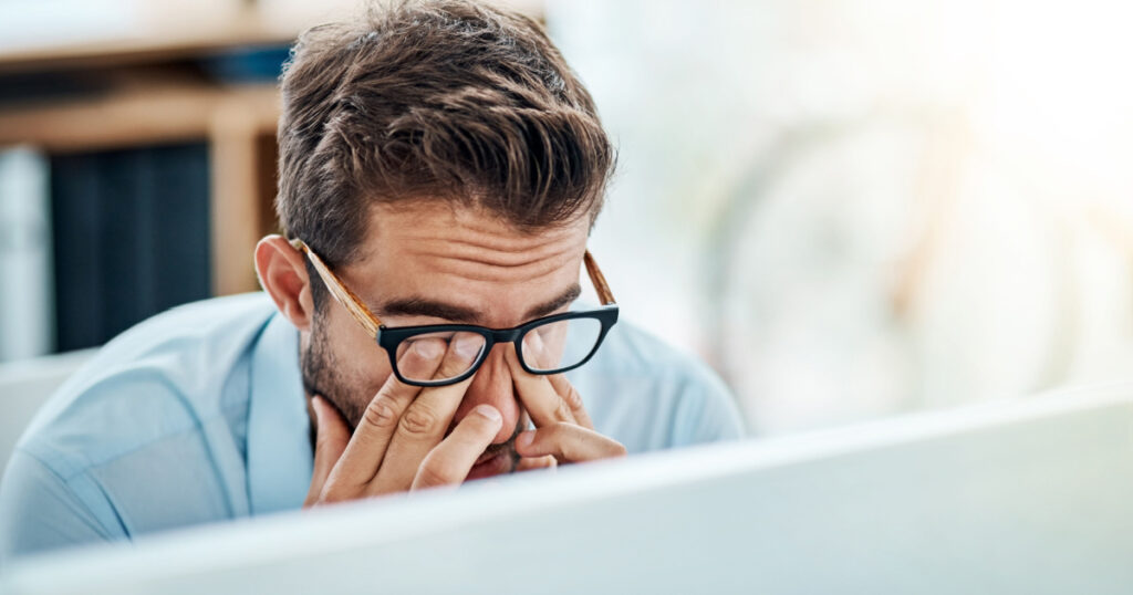 Business man, headache and pain, tired or fatigue in office while working on pc. Burnout, migraine and male person with depression, vertigo or brain fog, anxiety or mental health, stress or problem.