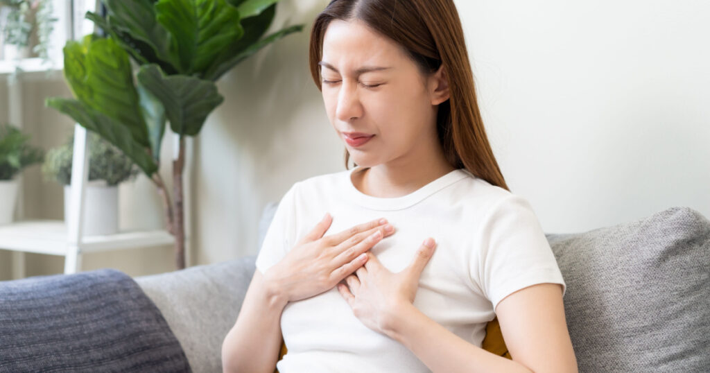 Acid reflux disease, suffer asian young woman have symptom gastroesophageal, esophageal, stomach ache and heartburn pain hand on chest from digestion problem after eat food, Healthcare medical concept