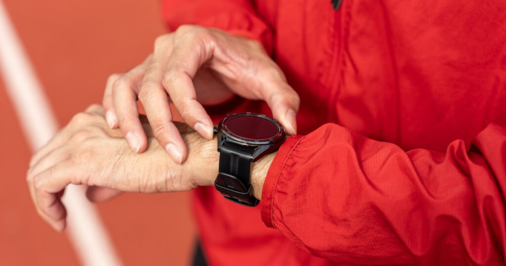 Close up young asian man press the button of smart watch for checking heart rate, distance, calories or anything about her running athlete workout equipment app technology monitor active gadget.