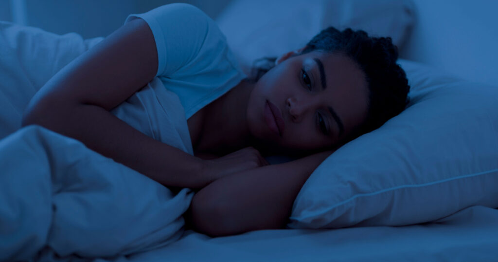 Awake sleepless upset black woman lying in bed alone at night, cant sleep, feeling lonely, suffering from depression or anxiety, experiencing difficulties with sleeping, resting in home interior