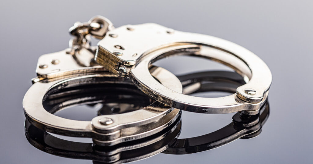 Shiny metal handcuffs on the mirror table.