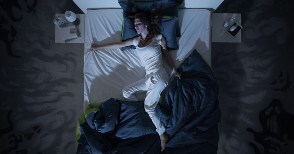 Nervous woman in bed have a nightmare at midnight, she is restless, top view