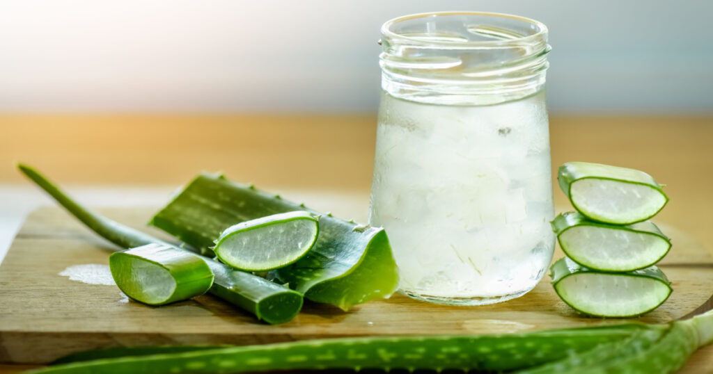 fresh aloe vera leaves and glass of aloe vera juice on wooden background