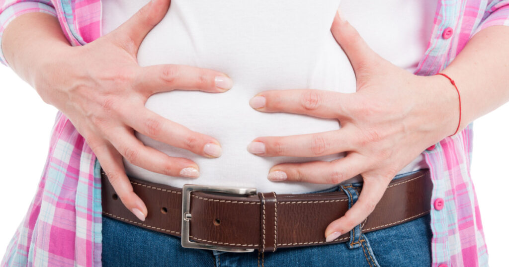 Close-up of female with bloated belly as flatulence concept isolated on white background