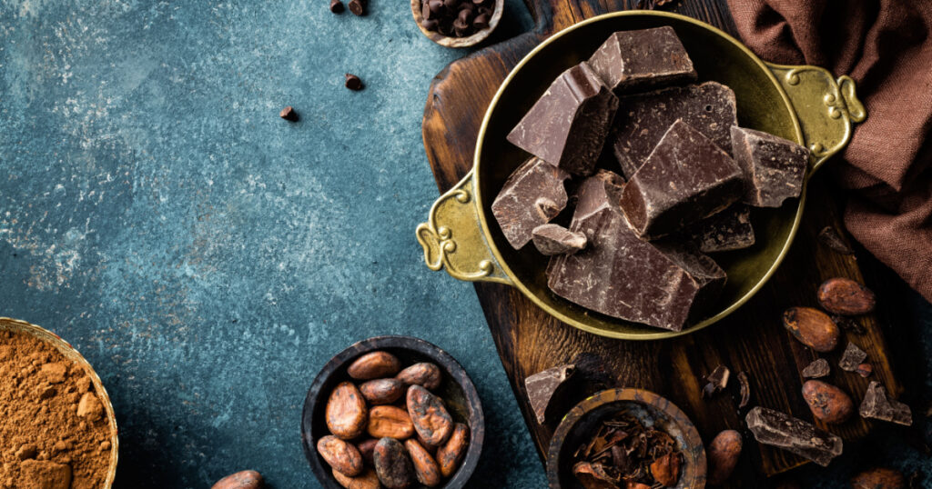 Dark chocolate pieces crushed and cocoa beans, culinary background, top view