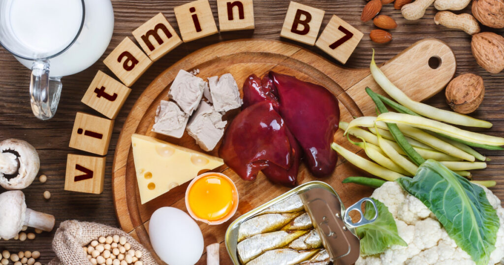 Foods rich in vitamin B7 (Biotin). Foods as liver, eggs yolk, yeast, cheese, sardines, soybeans, milk, cauliflower, green beans, mushrooms, peanuts, walnuts and almonds on wooden table
