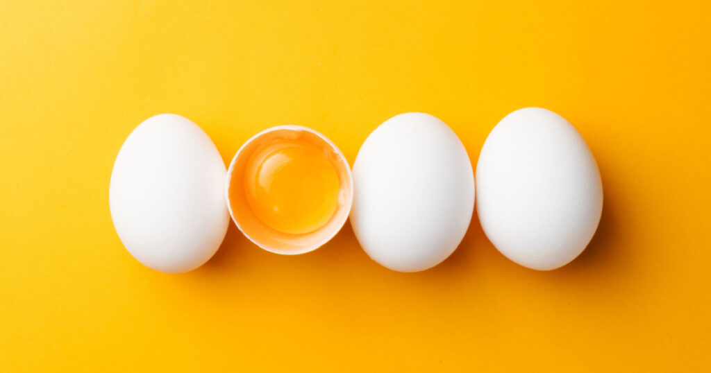 White eggs and egg yolk on the yellow background.