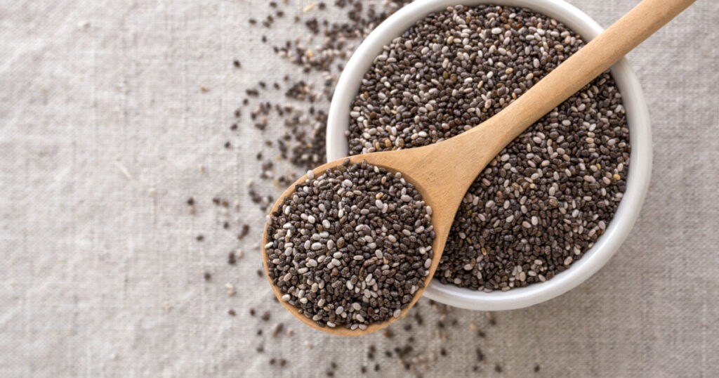 Chia seeds in wooden spoon and bowl from top view with space