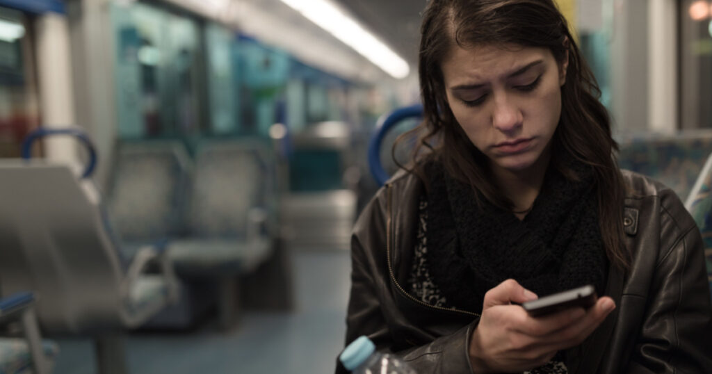 Sad depressive woman in train going home from work.Tired exhausted looking young lady getting away with train ride.Bored female person during commute time.Public transportation user.Using mobile phone
