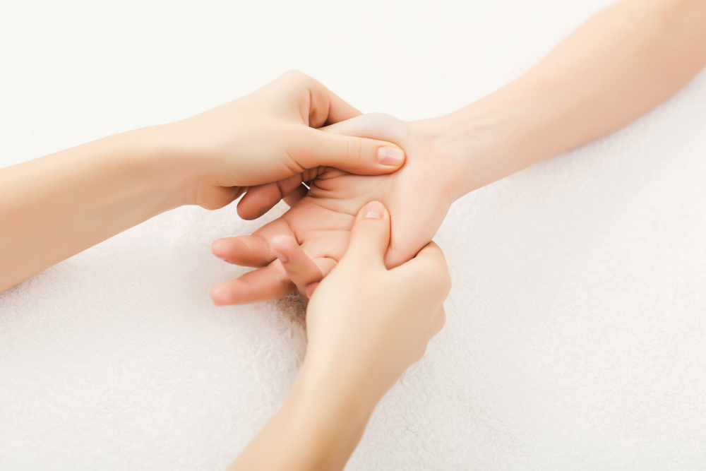 Hand massage. Physiotherapist pressing specific spots on female palm. Professional health and wellness acupressure manipulations, copy space, closeup