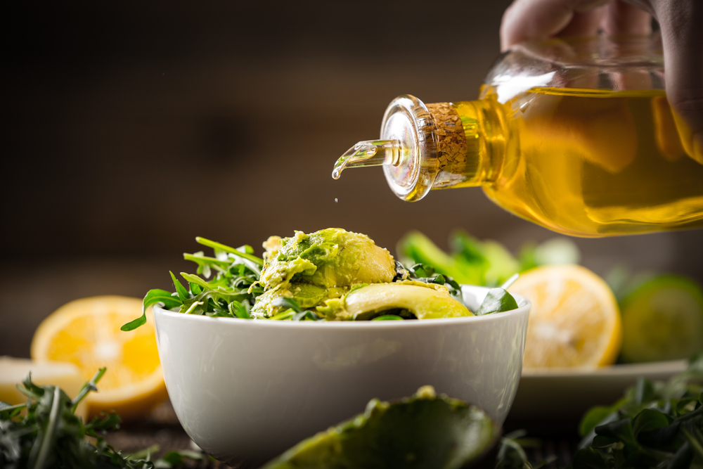 Preparation of avocados in green salad. Vegetables and a bottle of olive oil.