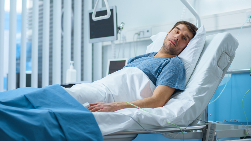 Seriously Ill Man Lying on a Bed in the Hospital. Monitors Show His Vital Signs. Ward is Clean and New.
