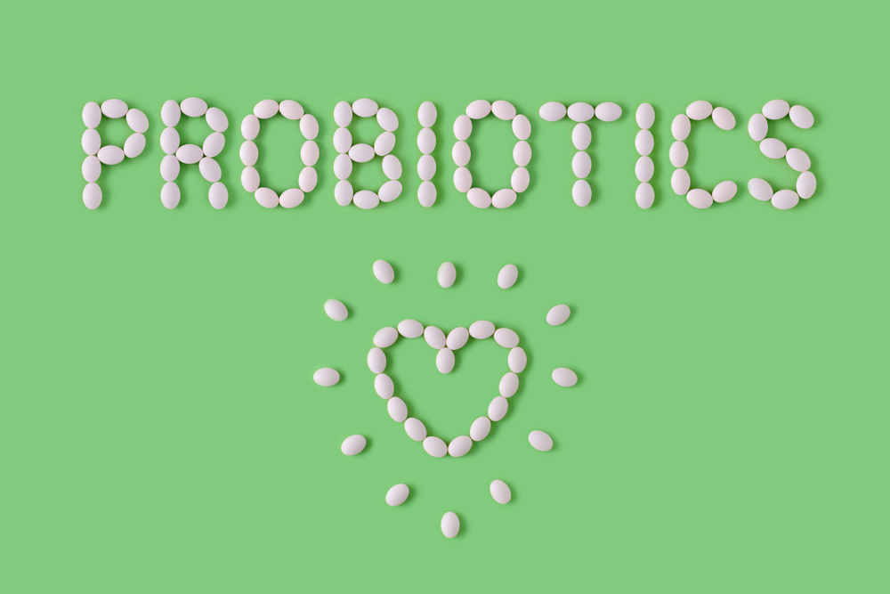 Probiotics word made of pills on green background. Flat lay, top view, free copy space. Natural medical pharmacy concept. Probiotics benefits.