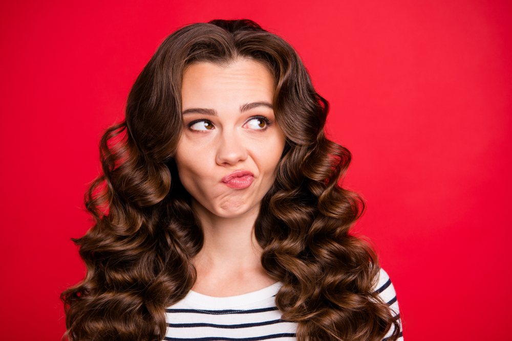 Close up portrait of attractive perfect hairdo she her girl looking up to empty space wondering not sure if did right way white striped pullover isolated on red vivid background
