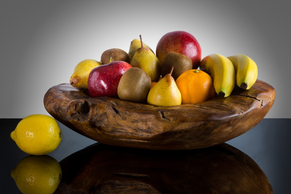 Fresh whole fruits in unique custom wood bowl - High quality healthy concept on black and gray background