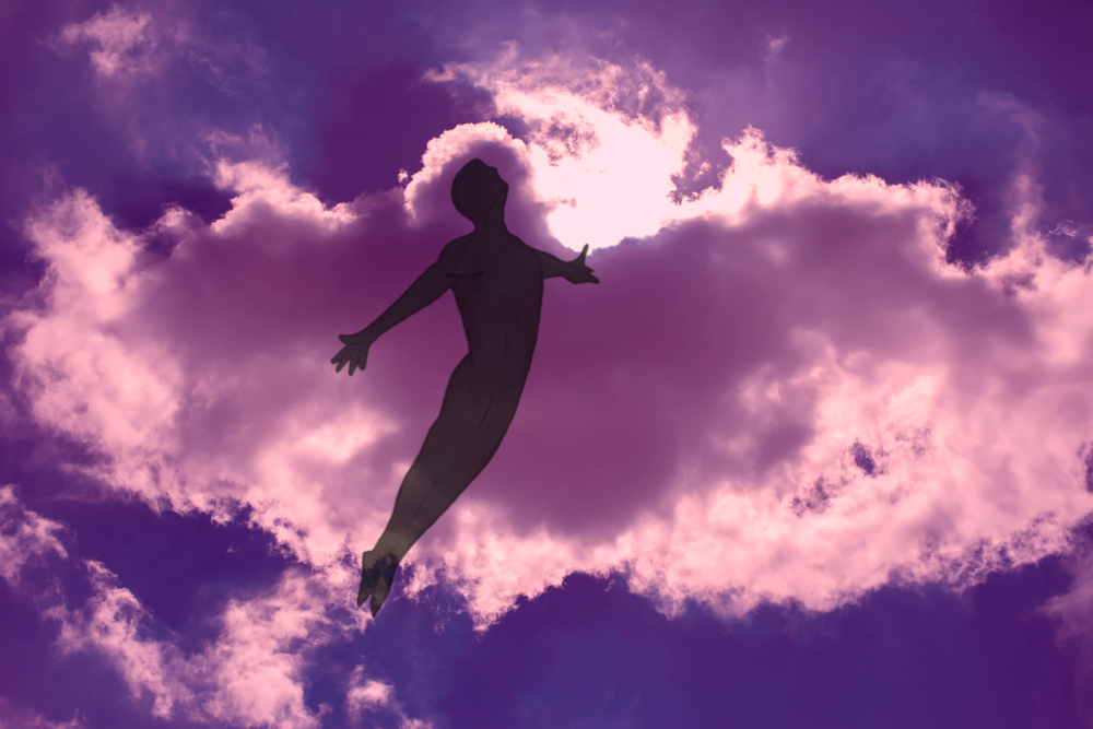 The man is flying in dreams through the cloudy night sky. The opened arms. Freedom and dreaming concept