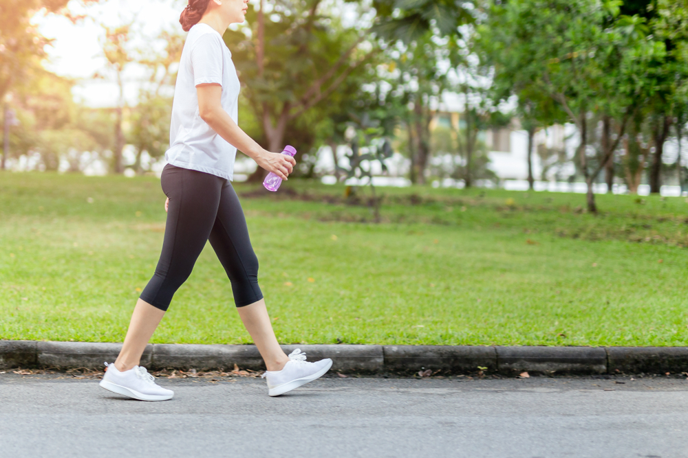 Woman walking in the park with bottle water in summer health care concept.