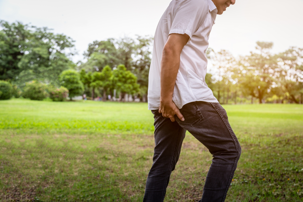 Asian young man has diarrhoea, holding her butt,hands touching his bottom in pain having hemorrhoids,person male scratching hand his itchying from pinworm infection,health problem,healthcare concept