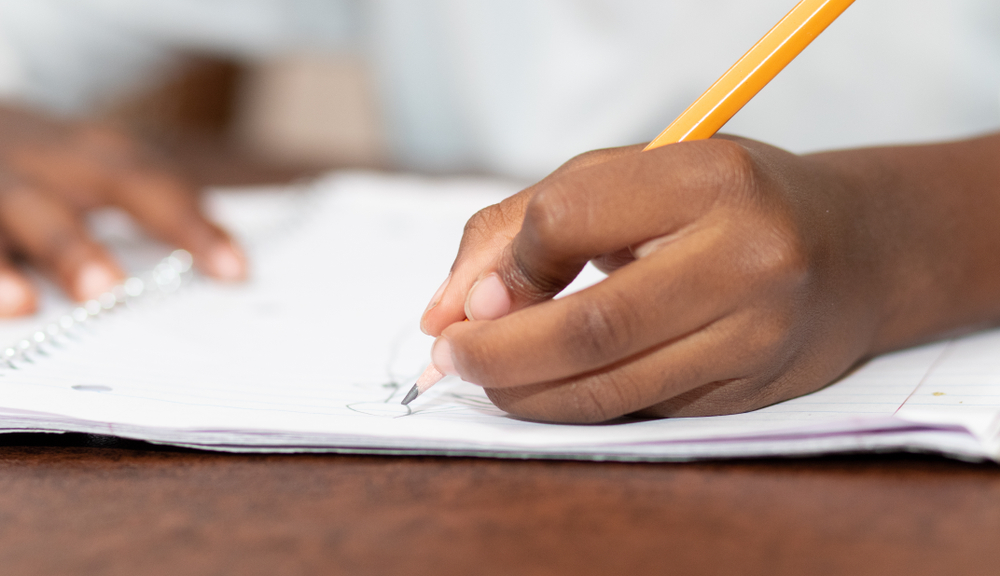 Little black girl drawing with her left hand.