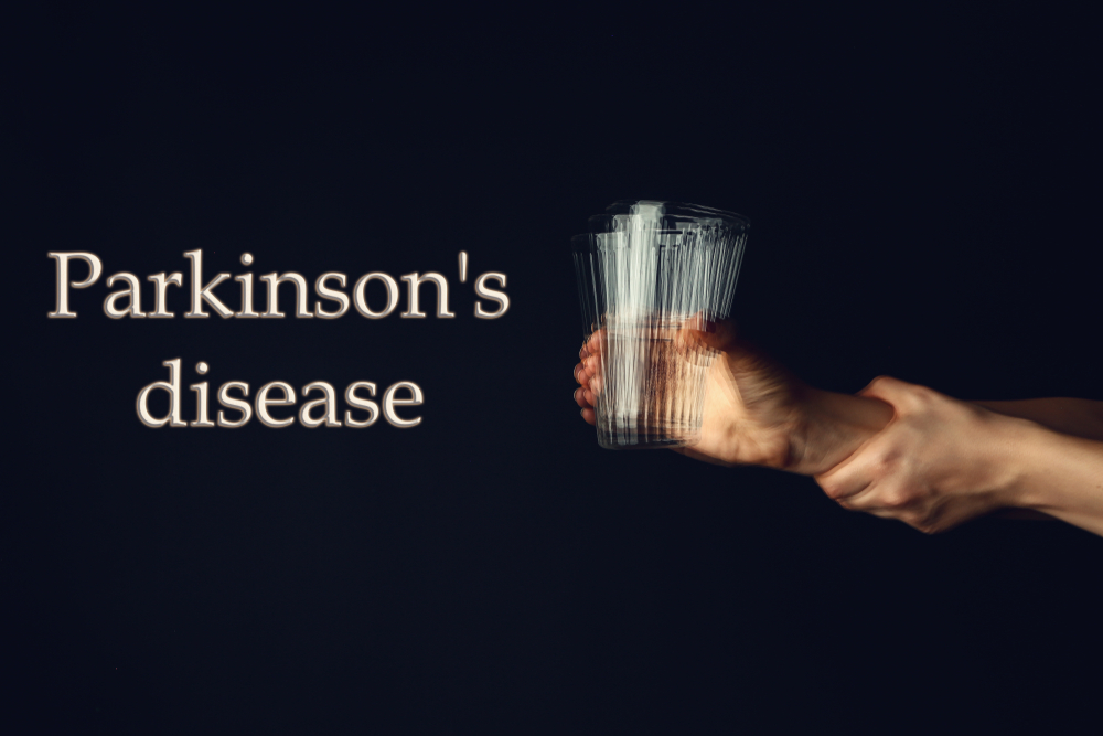 Trembling hands with glass of water and text PARKINSON'S DISEASE on dark background