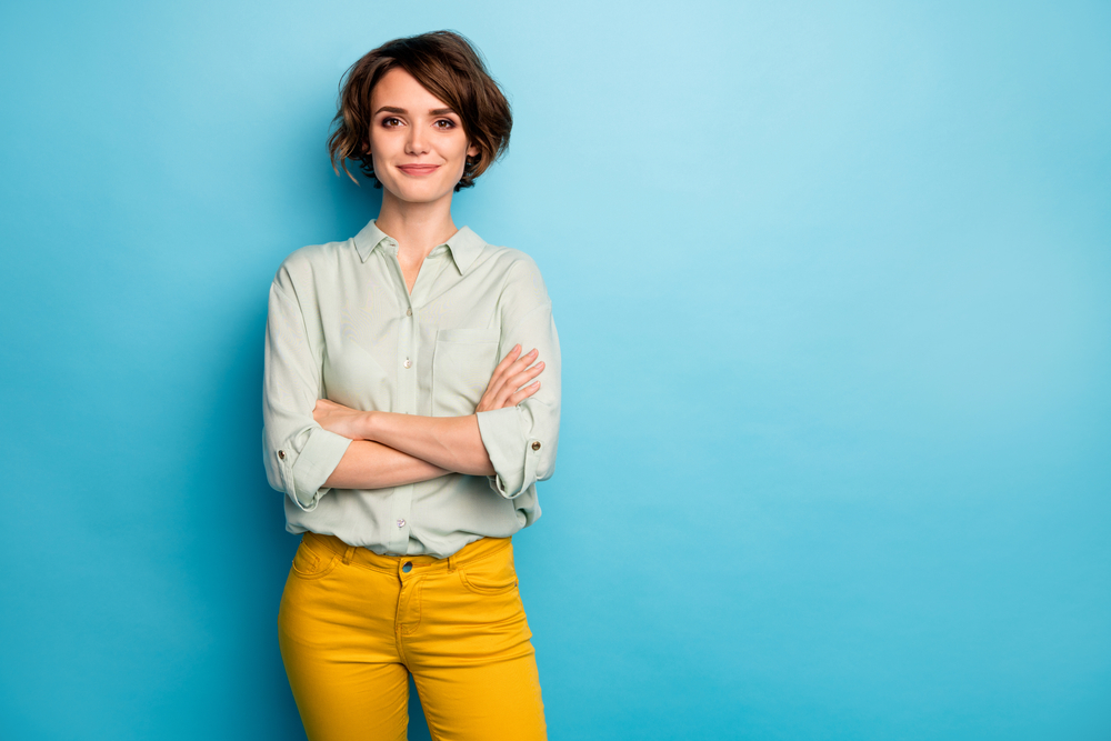 Photo of cool attractive business lady short hairstyle friendly smiling responsible person arms crossed wear casual green shirt yellow pants isolated blue color background