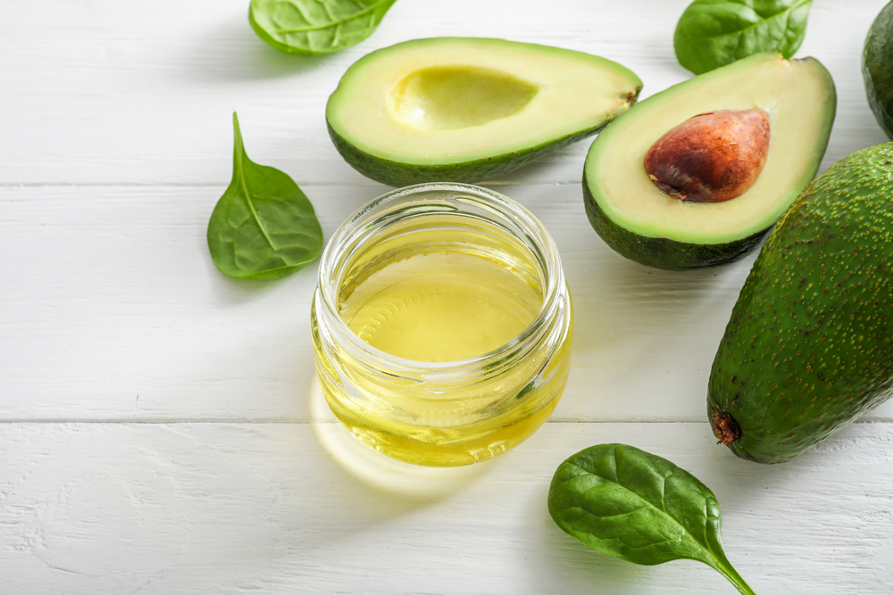Avocado fruits and avocado oil on white wooden background.