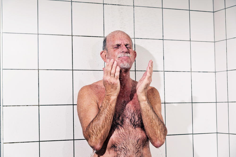 Senior man taking a shower in bathroom.
