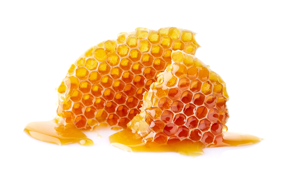 Honeycomb with honey drop on white background