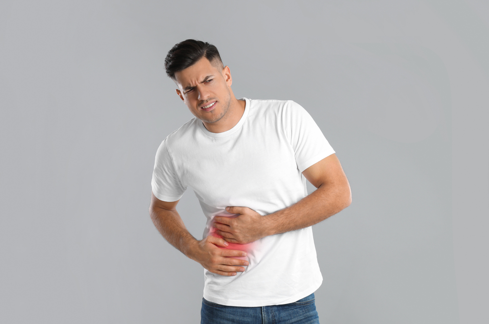 Man suffering from liver pain on grey background
