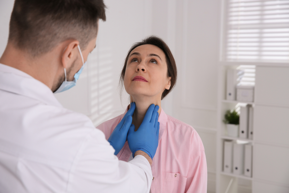 Doctor examining thyroid gland of patient in hospital
