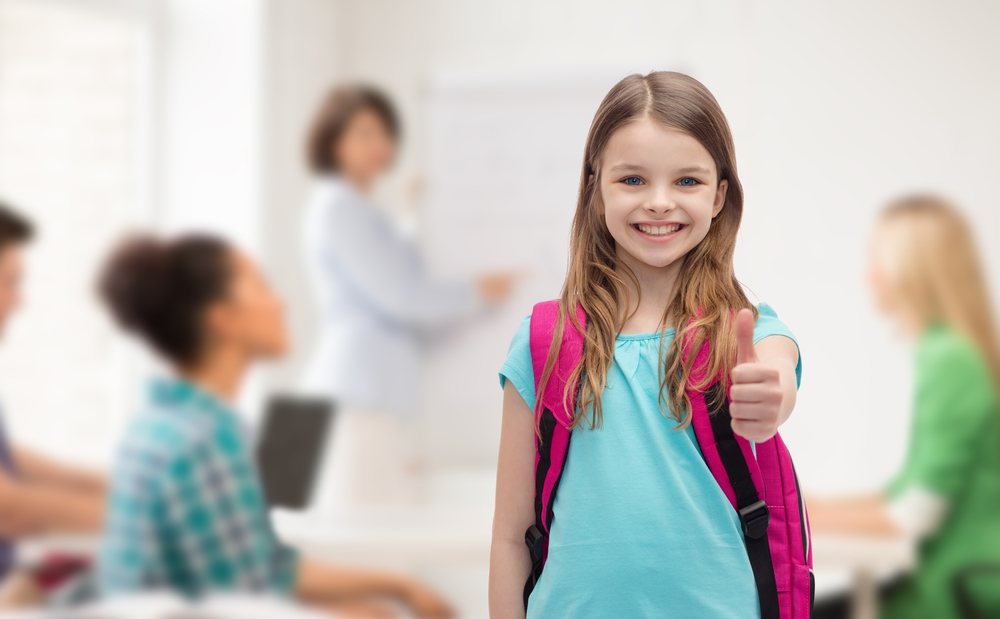 education, gesture and school concept - happy and smiling little girl with school bag showing thumbs up