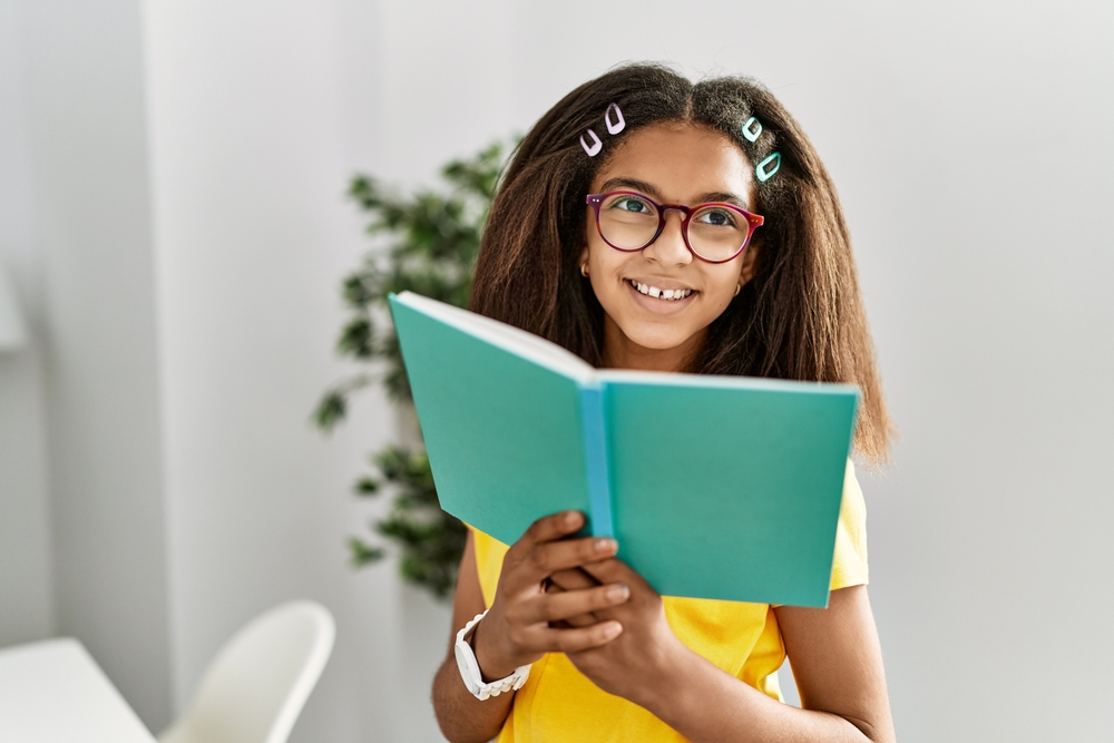 African american girl smiling confident reading book at home