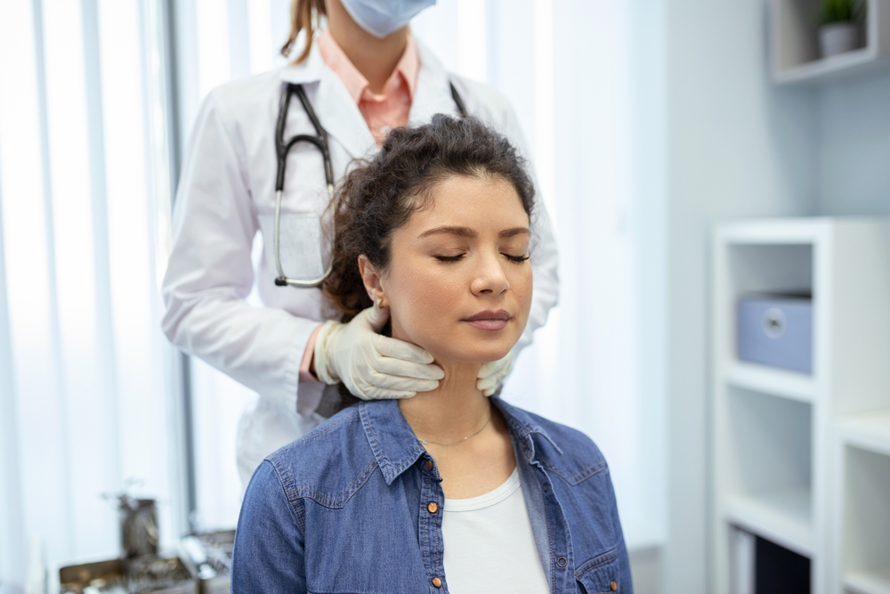 Endocrinologist examining throat of young woman in clinic. Women with thyroid gland test . Endocrinology, hormones and treatment. Inflammation of the sore throat